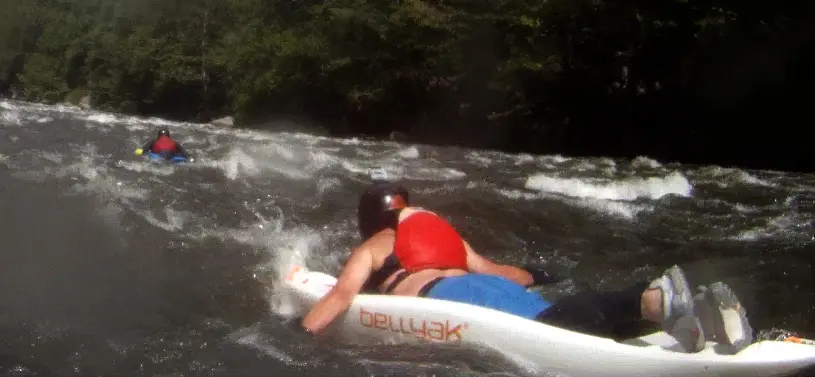 A rider lying on a white Bellyak in river current